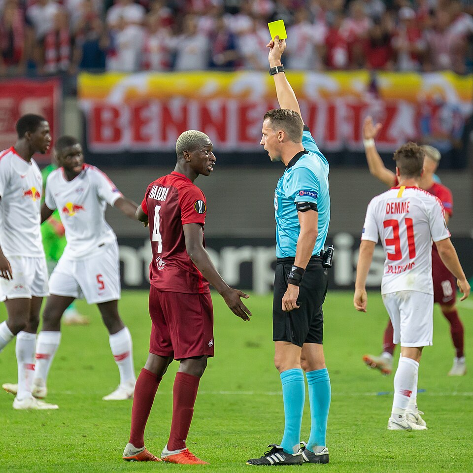 Arbitro mostrando tarjeta amarilla en un partido de futbol argentino